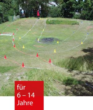 Auf einer Wiese ist mit Hütchen ein Fahrradparcour markiert.