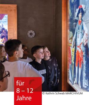 Eine Gruppe von Kindern schaut sich ein beleuchtetes Bild im Museum an