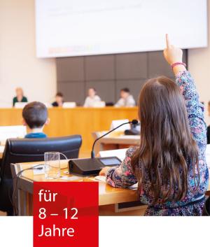Kinder sitzen an den Tischen des Mannheimer Gemeinderats. Ein Kind meldet sich