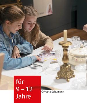 Zwei Mädchen sitzen an einem gedeckten Tisch und unterhalten sich