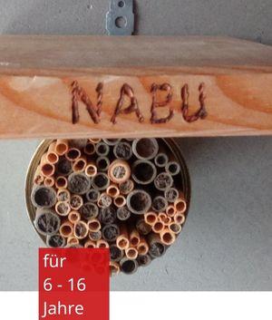 Nisthilfe für Insekten mit kleinen Röhrchen. Darüber ein Holzstück mit dem Wort NABU reingelötet.