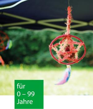 Ein roter Traumfänger tanzt im Wind an einem blauen Pavillon in der Natur