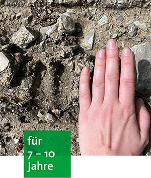 eine Hand liegt auf dem Waldboden neben einer Tierspur